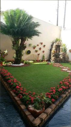 a lawn with red flowers and palm trees in the center is surrounded by brick edgings