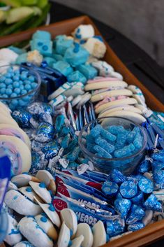 a tray filled with blue and white candies, marshmallows, and candy