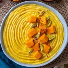 a white bowl filled with yellow sauce and chopped carrots on top of a table