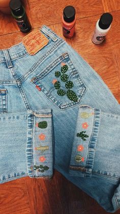 the jeans have cactus patches on them and are sitting on the floor next to other items