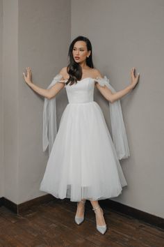 a woman in a white dress is posing with her hands up and arms out to the side