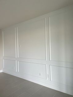 an empty room with white walls and wood paneling on the wall is shown in this image