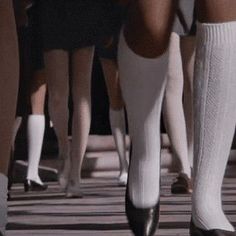 several women in white socks are walking down the street with their legs crossed and one is wearing black shoes