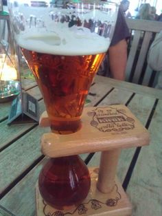 a glass of beer sitting on top of a wooden table