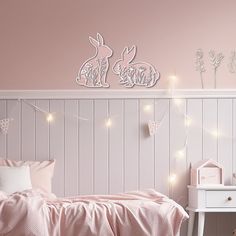 a bedroom with pink walls and white bedding is decorated with string lights that are strung across the headboard