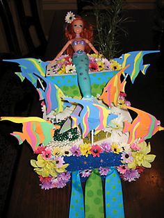 there is a cake made to look like a mermaid with flowers and butterflies on it