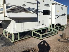 an rv parked on the side of a dirt road with mountains painted on it's sides