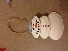 a white snowman ornament hanging from a string on a brown tablecloth