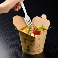 a person is holding a fork in a paper cup with food inside it on a table