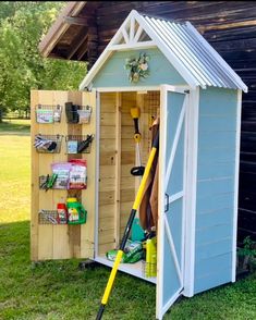 a shed that has some tools in it and is sitting on the grass with its door open