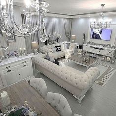 a living room filled with white furniture and chandelier