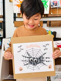 a young boy holding up a halloween card in front of his face with spider web on it