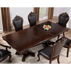 a dining room table with chairs and a bowl of fruit on the table in front of it