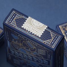 three blue playing cards sitting next to each other on top of a table with gold foil