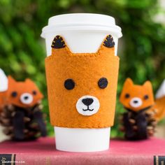 coffee cup cozyie made with felt and fabric fox head on top of a book