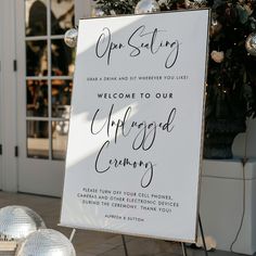 a welcome sign sitting on top of a metal stand next to a white building with lots of windows