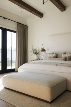 a large white bed sitting in a bedroom next to a sliding glass door and window