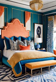 a bedroom with blue walls and orange bedding, gold headboard and foot board