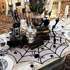 a table topped with lots of halloween decorations and candles on top of it in front of a fence