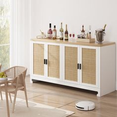 a room with a table, chairs and bottles on top of the cabinets in it