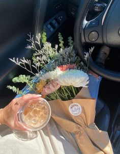 a woman is holding a bouquet of flowers in her car