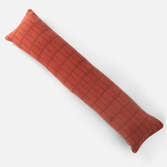 an orange pillow on a white surface with a red checkerboard pattern in the middle