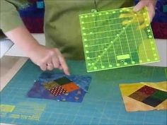 a person cutting up some paper on top of a blue table with green and yellow squares