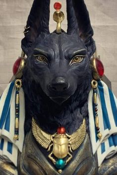 an egyptian cat statue with blue and white stripes on it's head, wearing gold jewelry