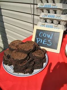 a table topped with chocolate cookies next to a sign that says cow pies on it