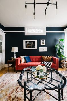 a living room filled with furniture and a red couch in front of a black wall