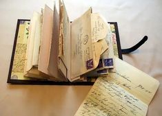 an open book sitting on top of a table next to some letters and envelopes