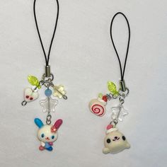 two key chains with charms attached to them on a white surface, one has an animal and the other has candy