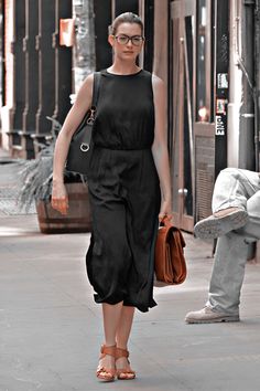 a woman in black dress walking down the street