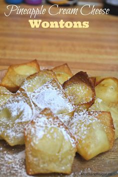 a wooden cutting board topped with creme cheese wontons covered in powdered sugar