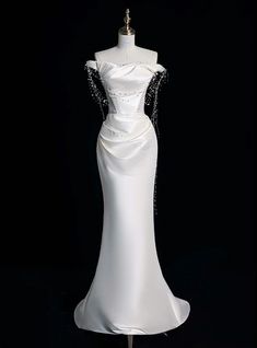 a white wedding dress on display in front of a black background with the back of it's neckline