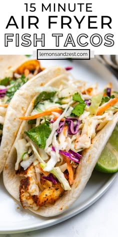 two fish tacos on a plate with lime wedges