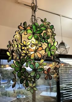 a chandelier hanging from the ceiling with green glass flowers and leaves on it