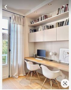 a desk with two chairs and a computer on top of it in front of a window