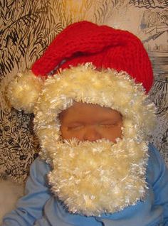 a baby wearing a santa claus hat while laying on top of a bed next to a wall