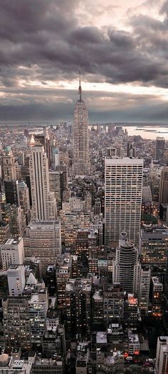 an aerial view of new york city with skyscrapers in the foreground and dark clouds overhead