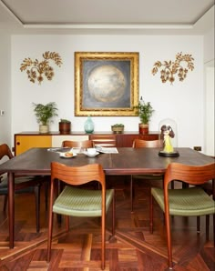 a dining room table with green chairs and a large painting on the wall behind it