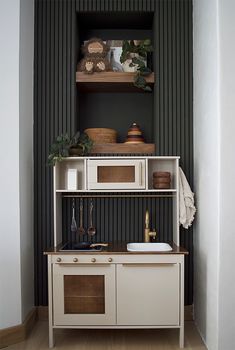 a white kitchen with black walls and wooden flooring in the corner, along with an open shelving unit