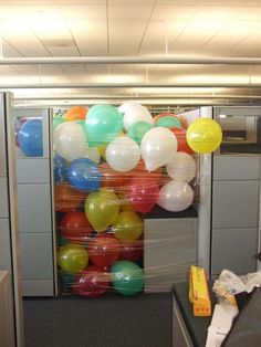 an office cubicle decorated with balloons and streamers