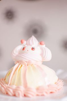 a cupcake with pink frosting and sprinkles sitting on a plate