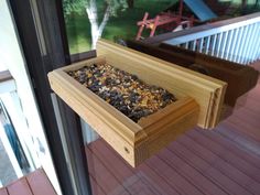 a window sill with bird seed in it on the outside decking next to a sliding glass door