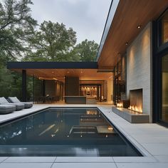 an outdoor swimming pool surrounded by lounge chairs and fire place in front of a house