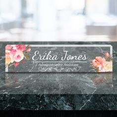 an acrylic business card with flowers on it sitting on a marble countertop