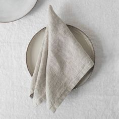 the linen napkin is folded on top of an empty plate and next to it are two plates