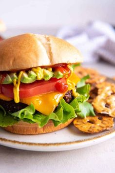 a cheeseburger with lettuce, tomato and onion on a plate next to crackers