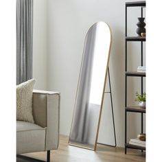 a large mirror sitting on top of a wooden floor next to a white couch in a living room